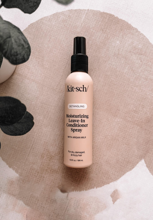 Kit-sch Moisturizing Leave-In Conditioner Spray bottle on a textured beige background