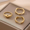 Three gold rings on a beige textured surface