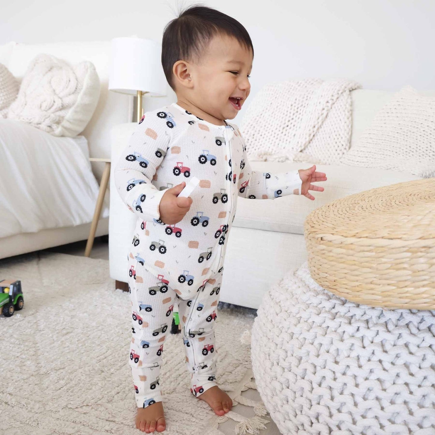 Child wearing pajamas with vehicle patterns in a cozy living room.