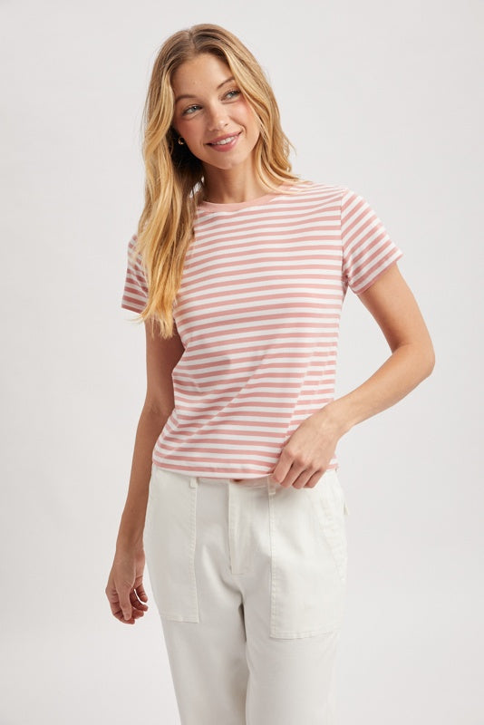 Woman wearing a pink and white striped t-shirt and white pants on a light gray background