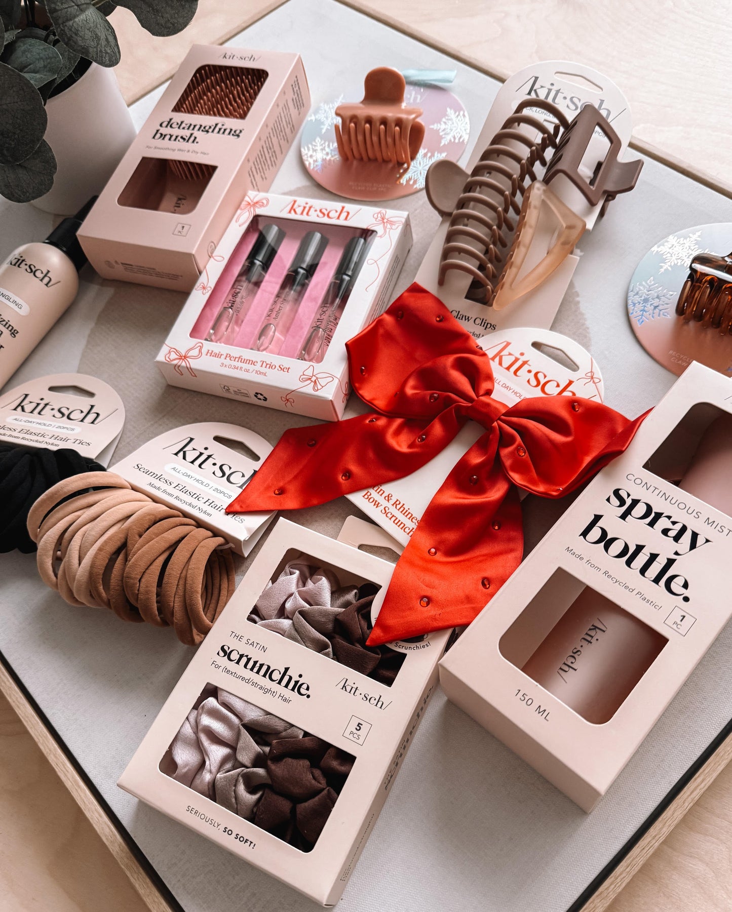 Kitsch hair accessories including hair ties, clips, and a spray bottle on a white surface.