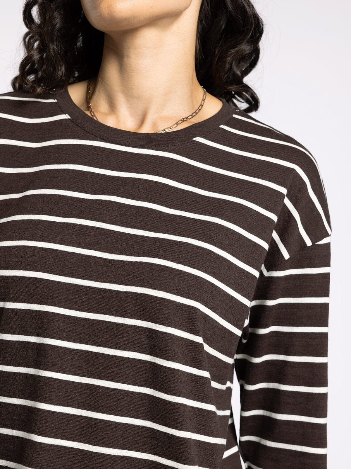 Close-up of a person wearing a black and white striped shirt on a plain background