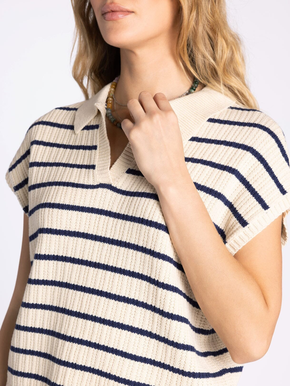 Woman wearing a beige and navy striped shirt against a white background