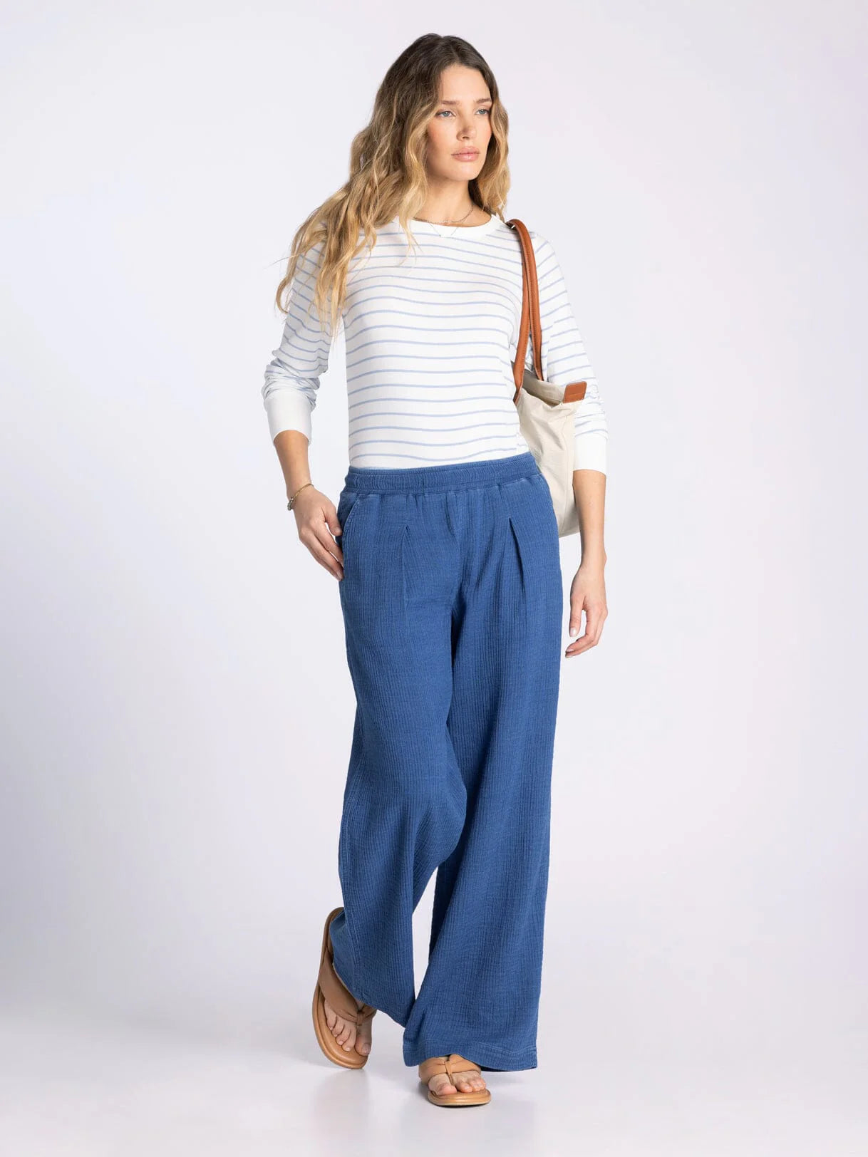 Woman wearing a white striped shirt and blue pants on a white background