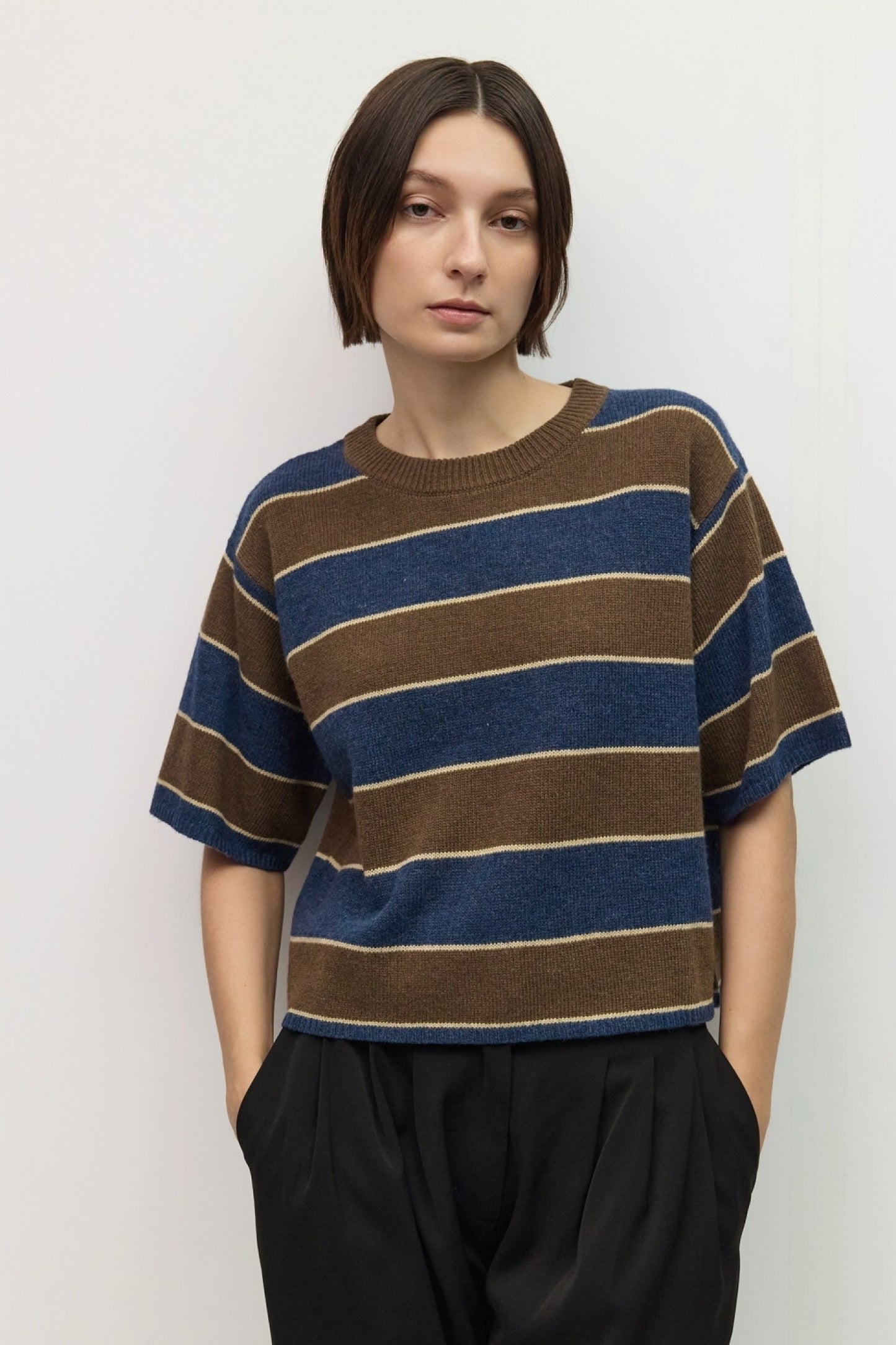 Person wearing a brown and blue striped sweater against a white background