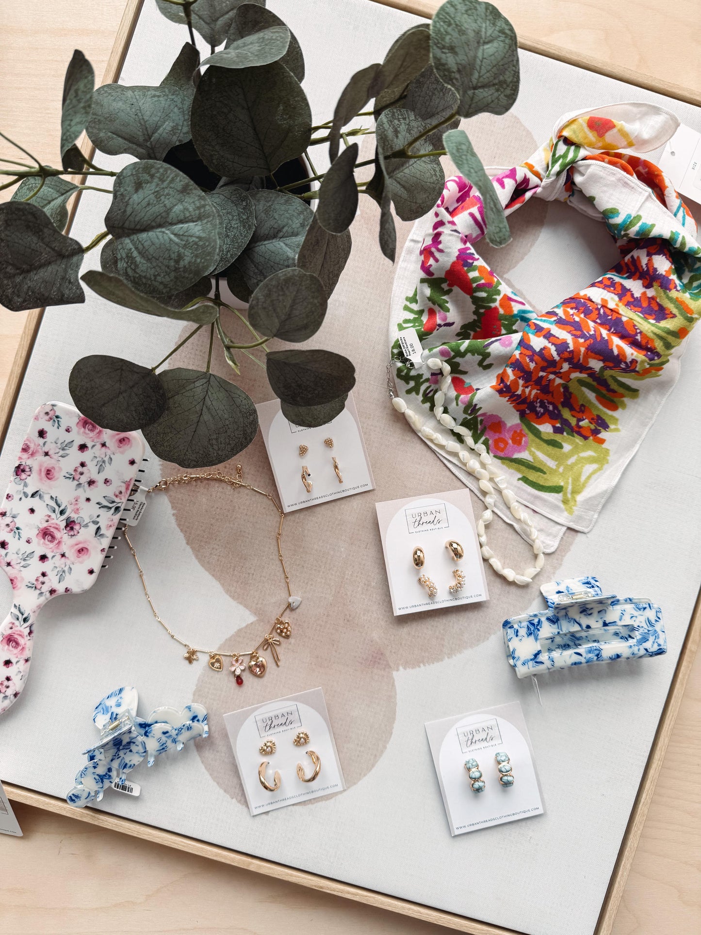 Jewelry and hair accessories on a light surface with green leaves.