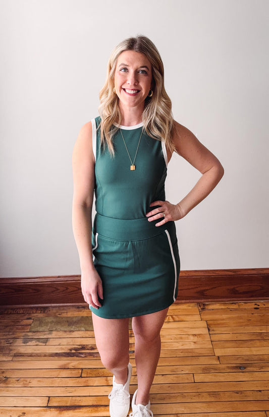 Woman wearing a green dress with a white stripe on a wooden floor.