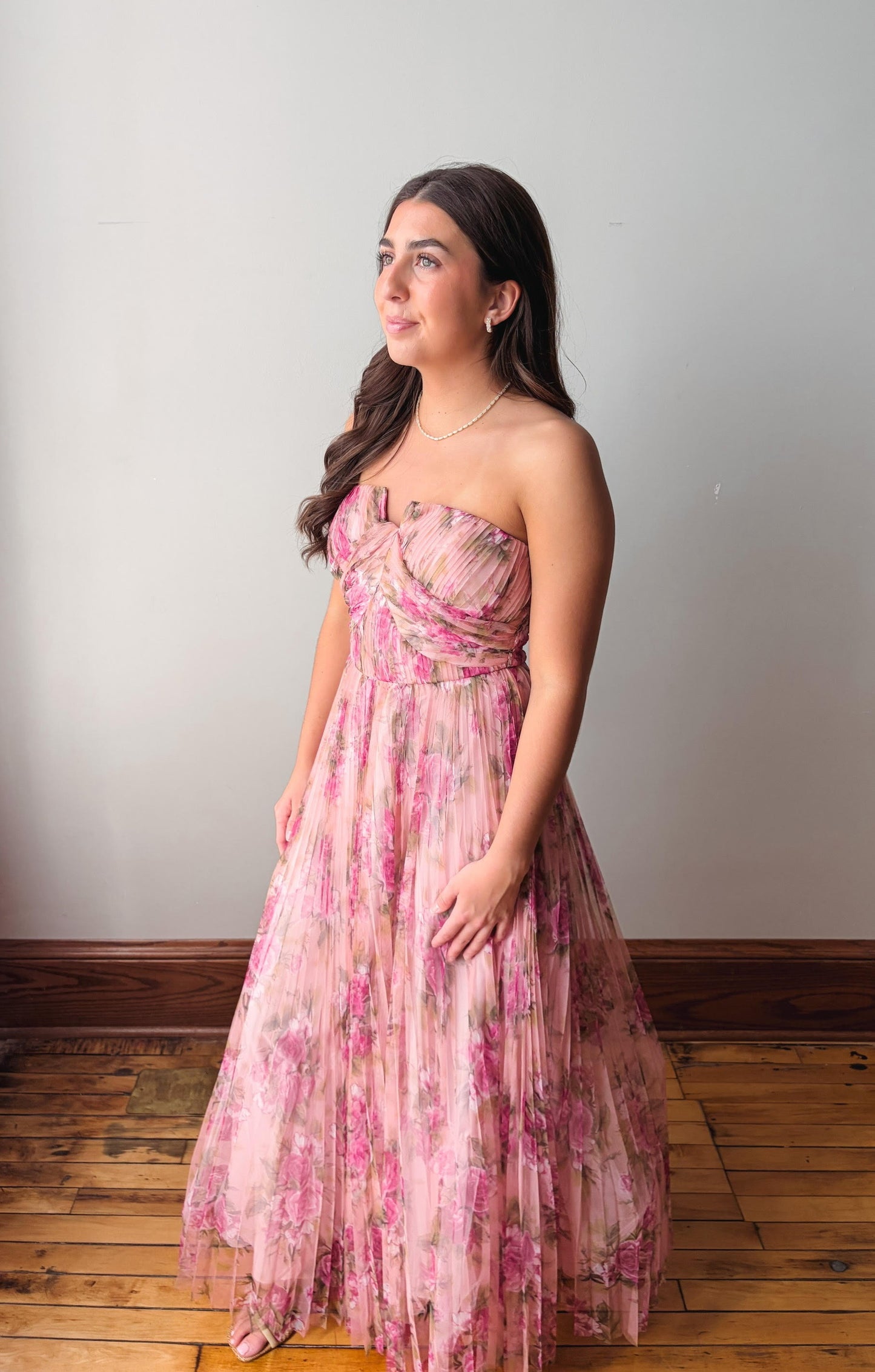 Woman wearing a pink floral dress against a plain background