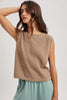 Woman wearing a beige sleeveless knitted top against a plain background