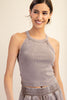 Woman wearing a gray tank top and pants against a plain background