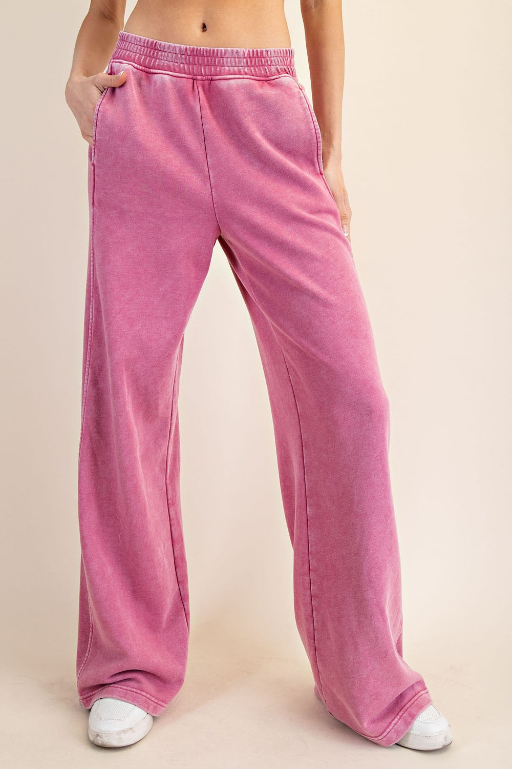 Pink velour pants worn by a person on a beige background