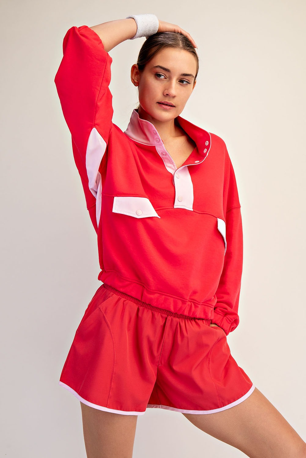 Woman wearing a red outfit with white accents on a plain background