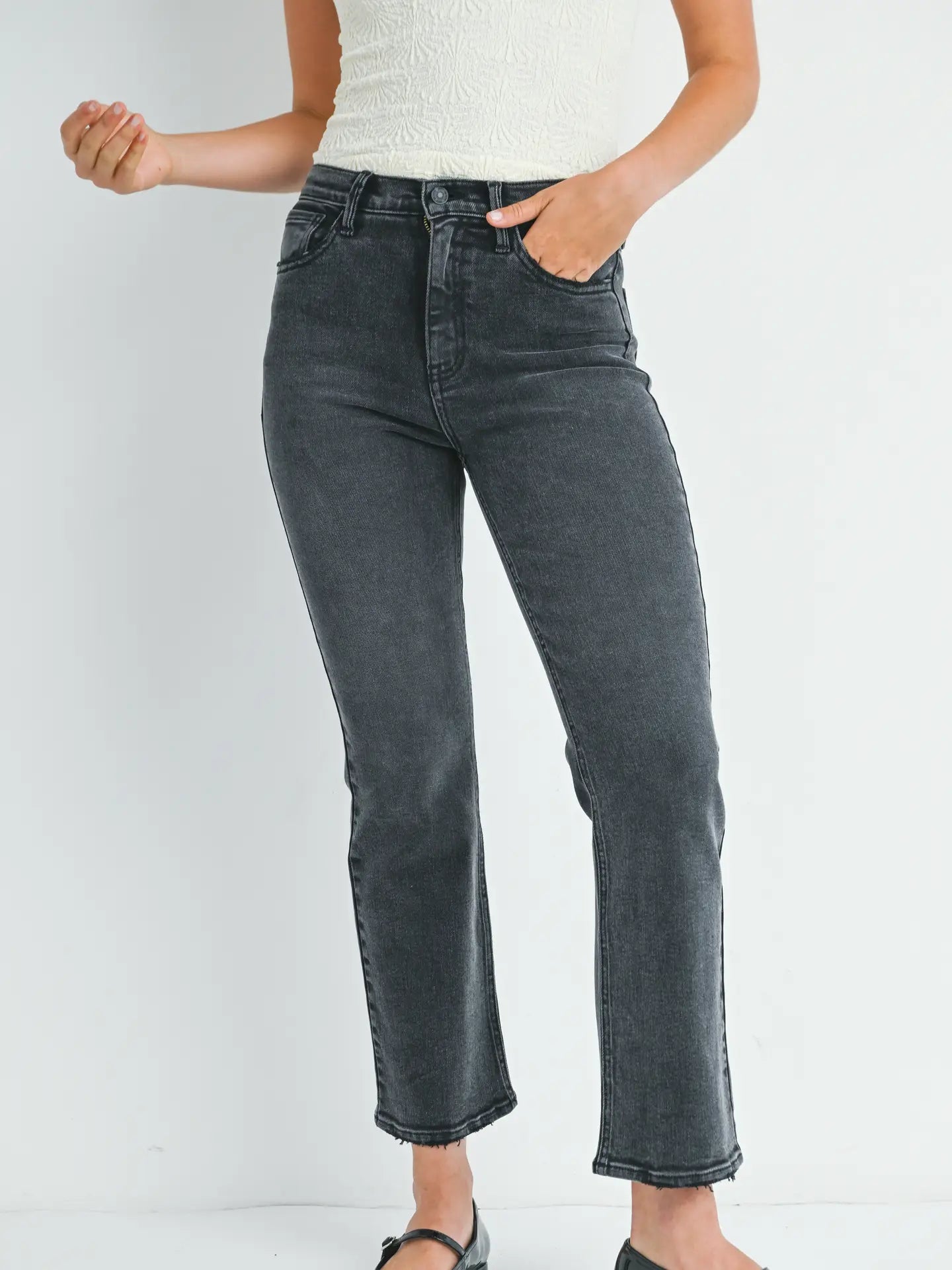 Person wearing black straight-leg jeans on a white background