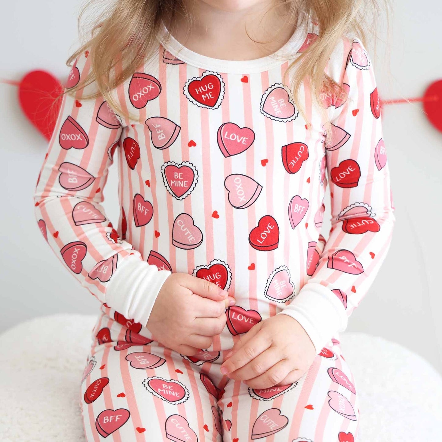 Child wearing pajamas with heart patterns on a light background