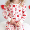 Child wearing pajamas with heart patterns on a light background