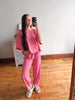 Person wearing a pink outfit taking a mirror selfie in a room with wooden flooring.