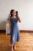 Woman taking a mirror selfie wearing a blue dress in a room with wooden flooring.
