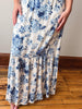Person wearing a white dress with blue floral pattern on a wooden floor.