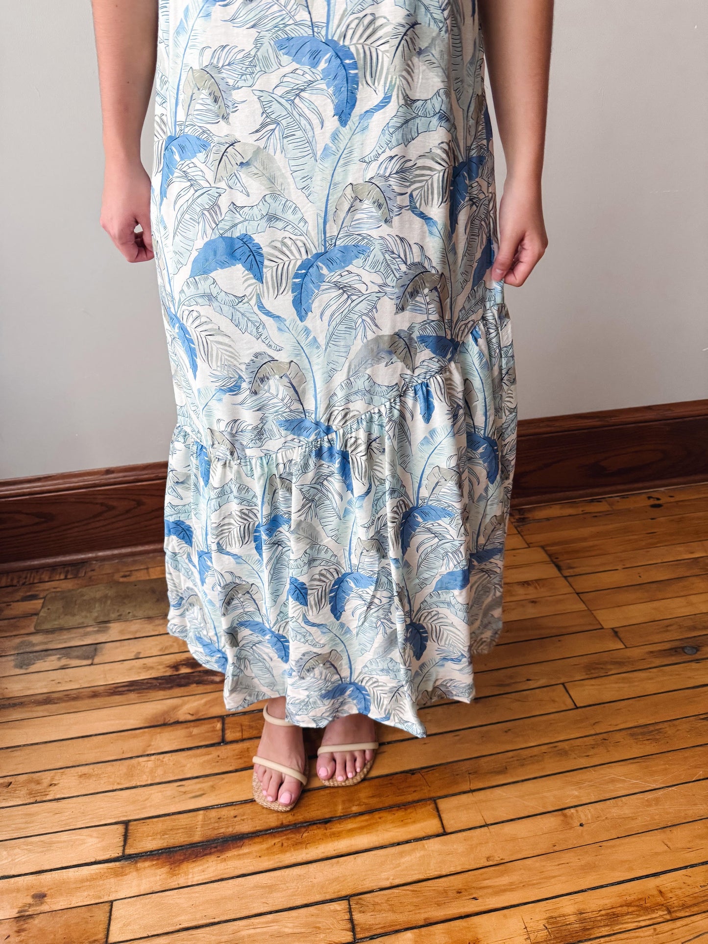 Person wearing a long floral dress on a wooden floor.