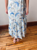 Person wearing a long floral dress on a wooden floor.