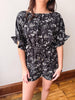 Black floral romper worn by a person against a plain background
