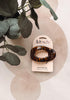 A tortoiseshell flat cloud hair clip by kitsch on a beige card, styled with green eucalyptus leaves on a patterned beige background.