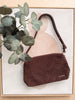 Brown textured handbag with a plant on a light background