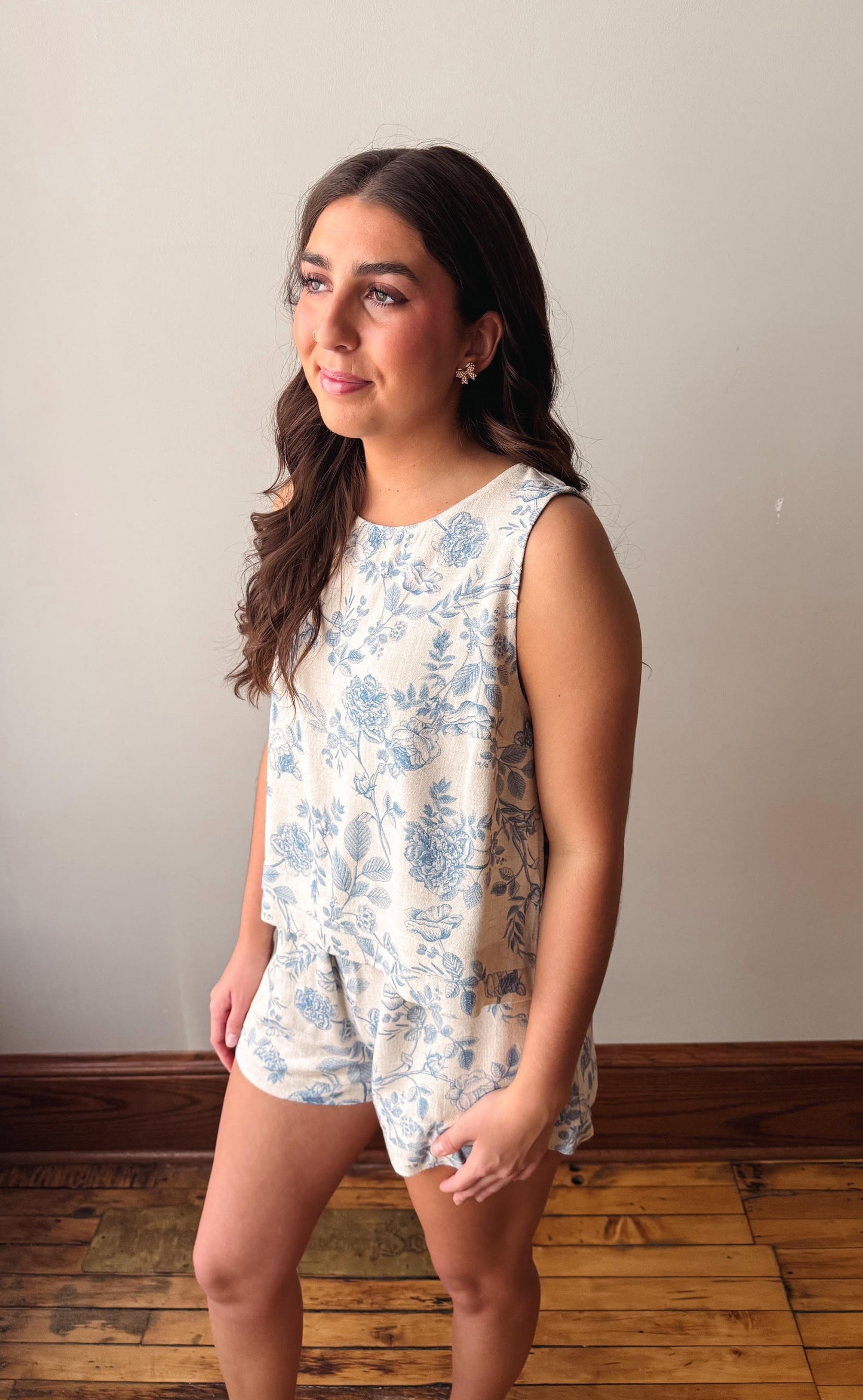 Woman wearing a white floral romper against a plain background