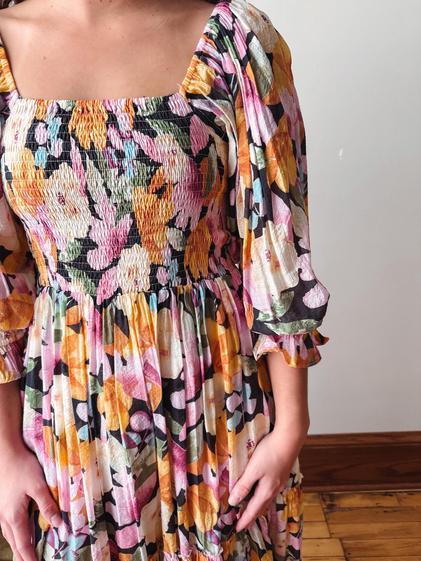 Multicolored patterned dress with smocked bodice and balloon sleeves on a plain background