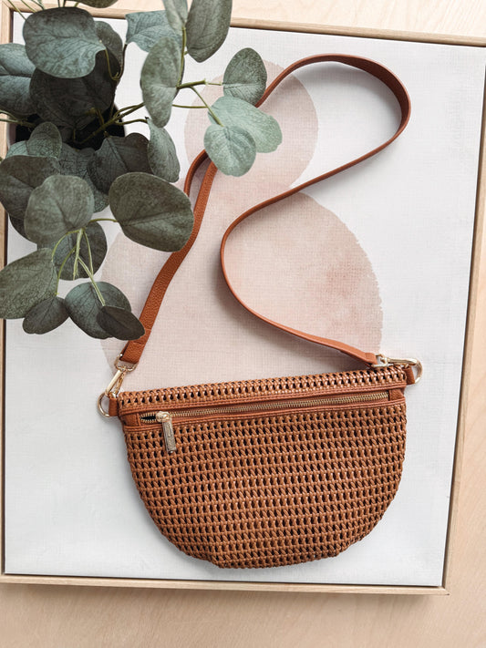 Brown woven handbag with a tan strap on a light background