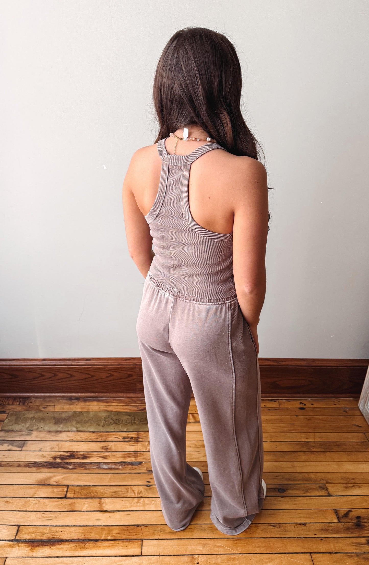 Person wearing a matching tank top and pants set on a wooden floor.