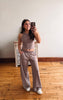 Woman taking a mirror selfie wearing a brown top and matching pants in a room with wooden flooring.