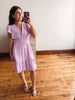 Woman taking a mirror selfie wearing a light purple dress on a wooden floor.