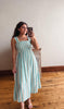 Woman taking a mirror selfie wearing a striped dress in a room with wooden flooring.