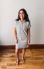 Woman wearing a striped dress standing on a wooden floor with a white wall background