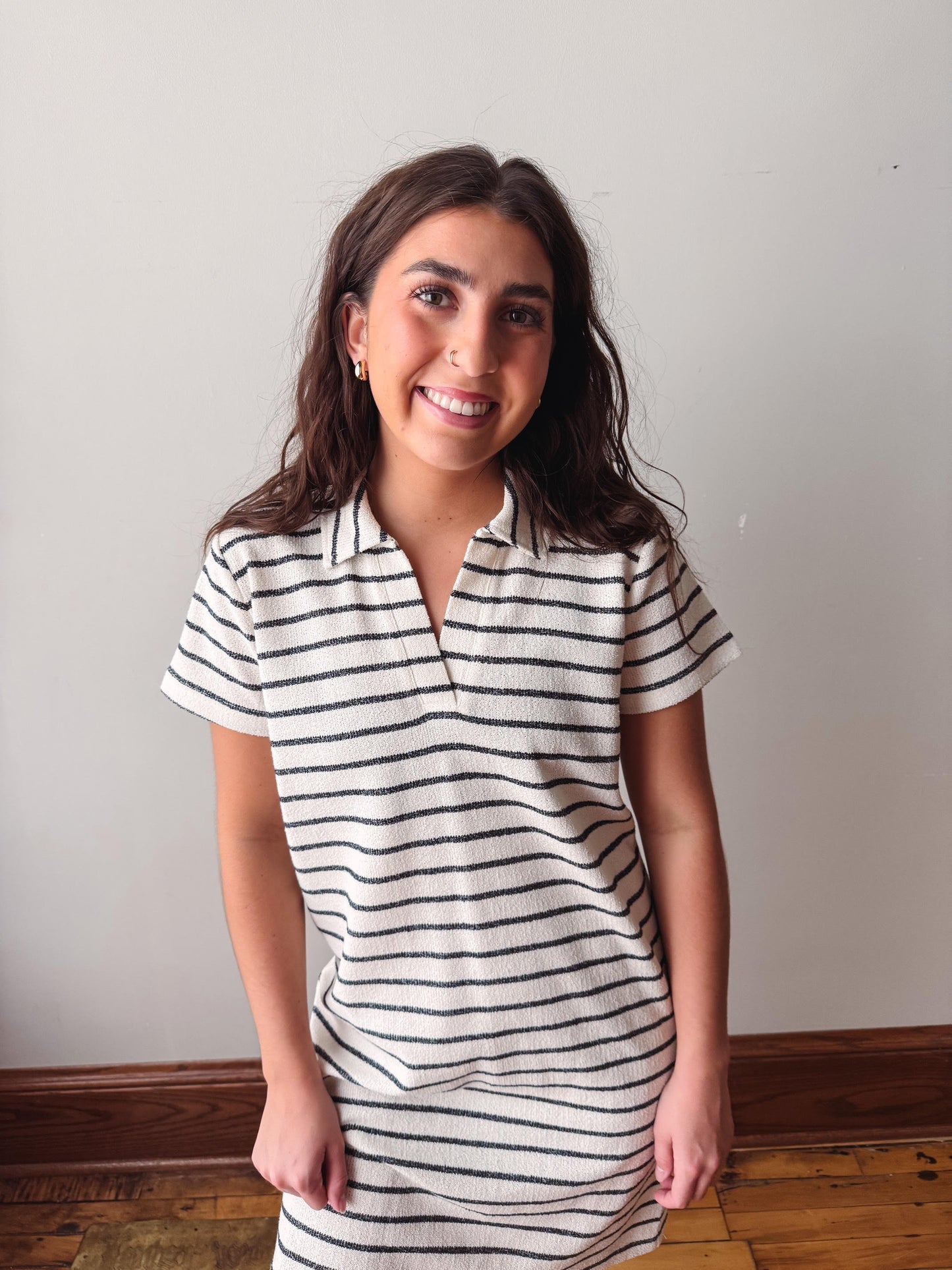 Woman wearing a black and white striped dress against a plain background