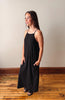 Woman wearing a black dress standing on a wooden floor with a plain wall background