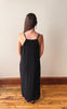 Woman wearing a black striped dress standing against a plain wall.
