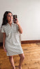 Woman taking a mirror selfie wearing a black and white striped dress.