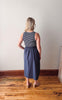 Woman wearing a striped top and denim skirt standing on a wooden floor with a white wall background