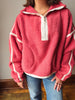 A person wearing a coral pink sherpa fleece half-zip pullover with white contrast trim and white piping details, paired with blue jeans.
