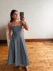 Woman taking a mirror selfie wearing a blue striped dress in a room with wooden flooring.