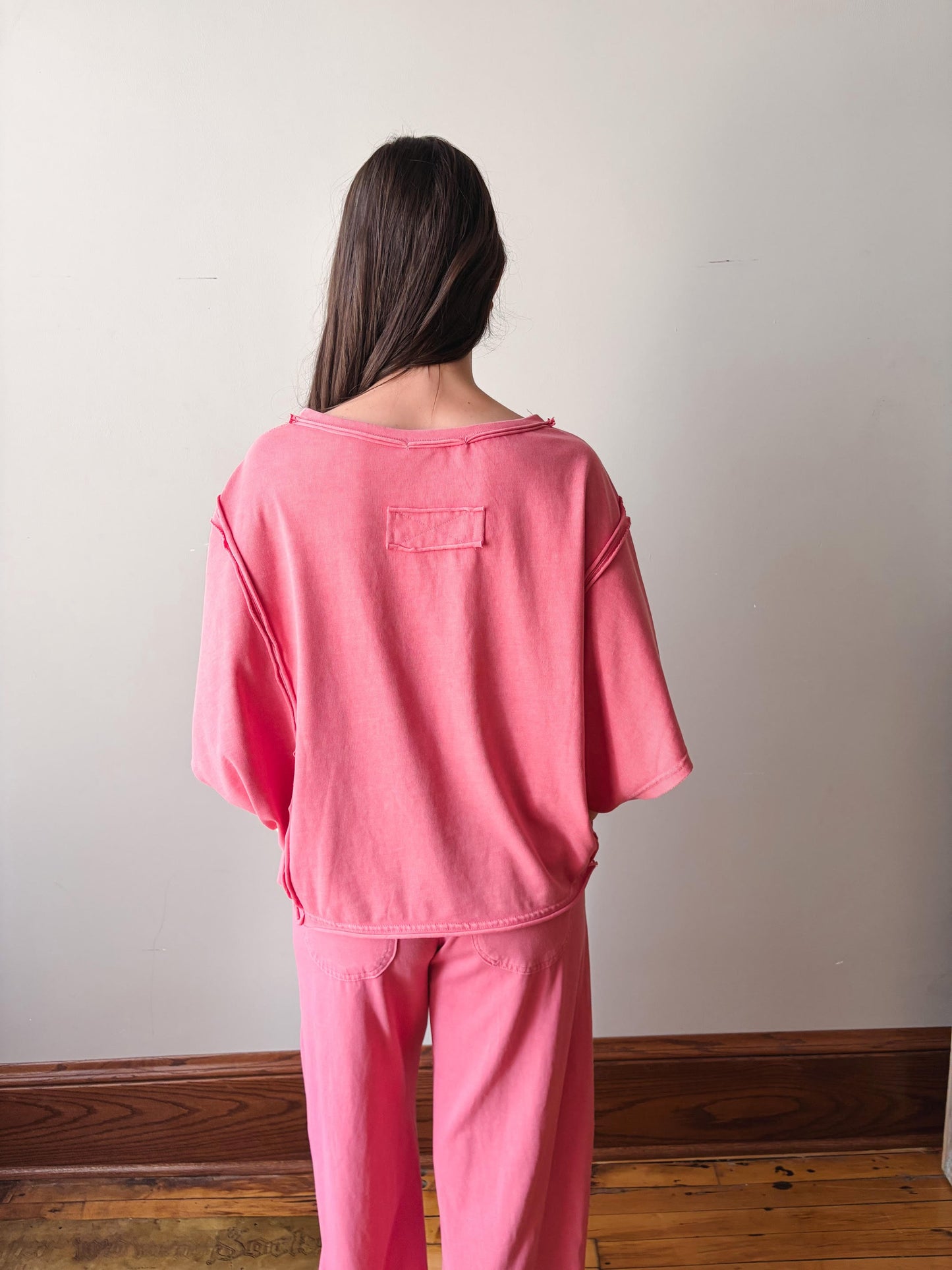 Person wearing pink pajamas standing against a plain wall.