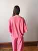 Person wearing pink pajamas standing against a plain wall.