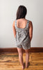 Woman wearing a floral romper standing on a wooden floor with a white wall background