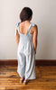 Woman wearing a light blue jumpsuit with thin straps in a minimal indoor setting.