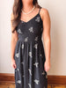 Woman wearing a black dress with white floral patterns against a plain background