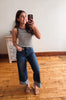 Woman taking a mirror selfie wearing a striped shirt and jeans in a room with wooden flooring.