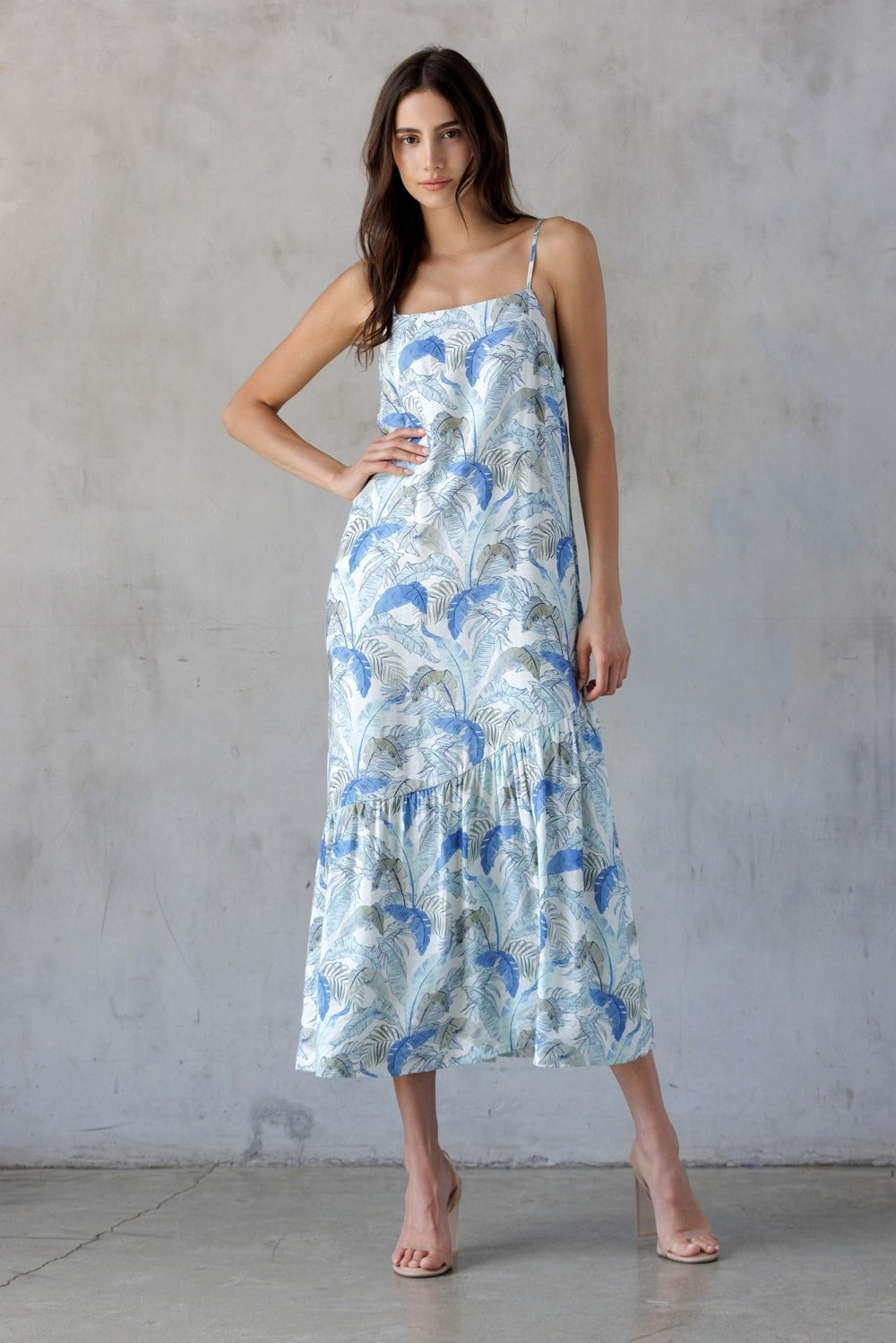 Woman wearing a floral dress against a gray concrete wall.