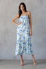 Woman wearing a floral dress against a gray concrete wall.